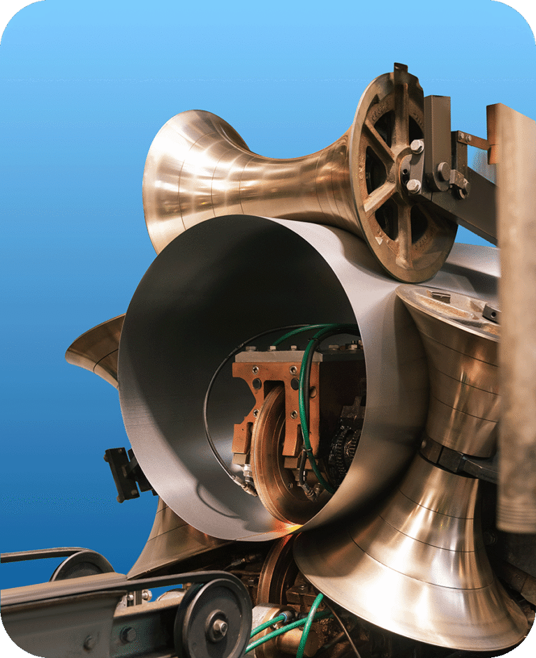A 205 litre steel drum body is being welded together into a cylinder, during an industrial manufacturing process.