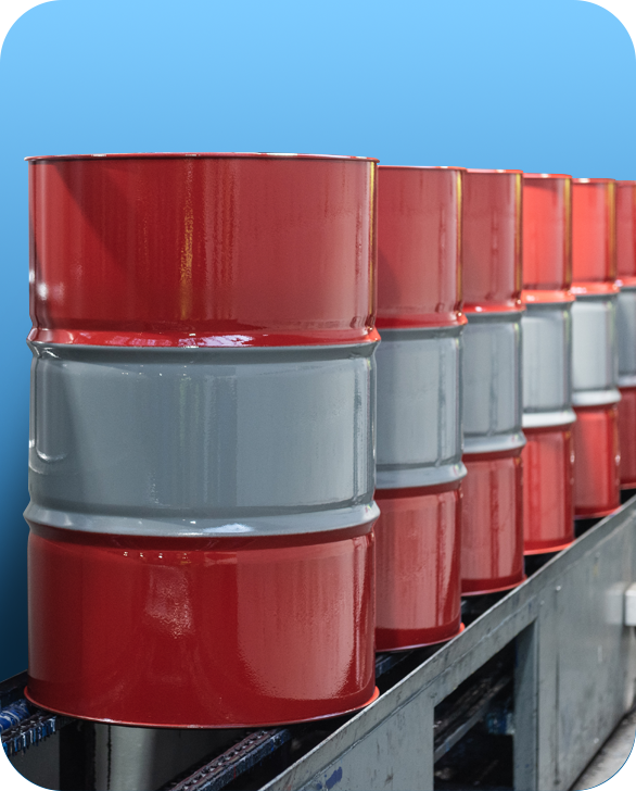 New, red and white steel drums on a conveyor belt, heading towards an industrial oven for curing, as part of the Ramsden Drums services.